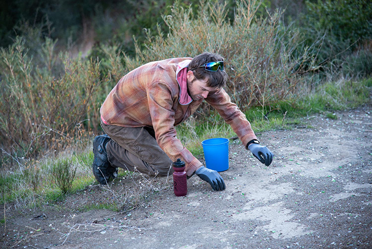 A man cleaning up garbage at the side of the roadway - Image &copy; Bryant Baker